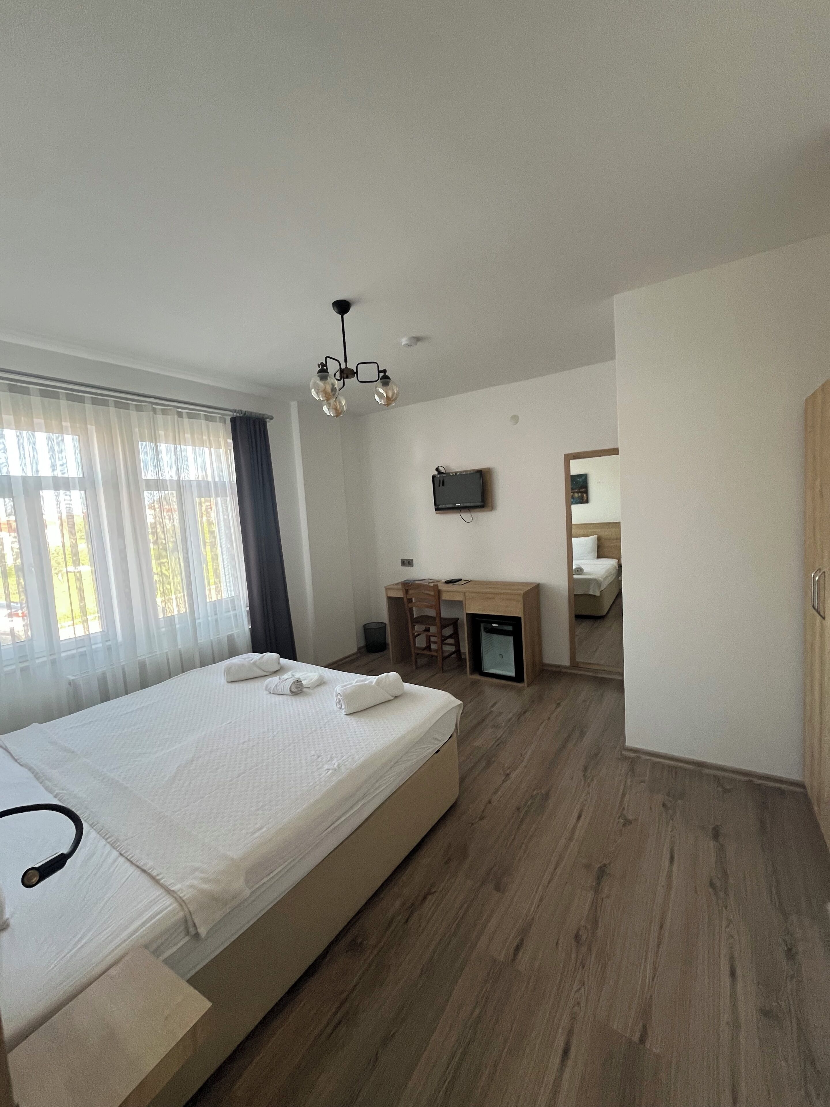 Un dormitorio con cama, escritorio, silla, televisión y armario.