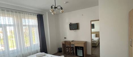 Un dormitorio con cama, escritorio, silla, televisión y armario.