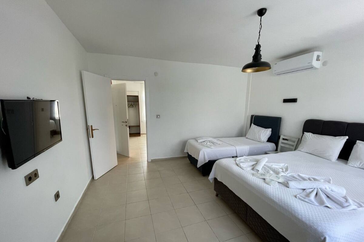 A hotel room with two beds, a TV, and an air conditioning unit.