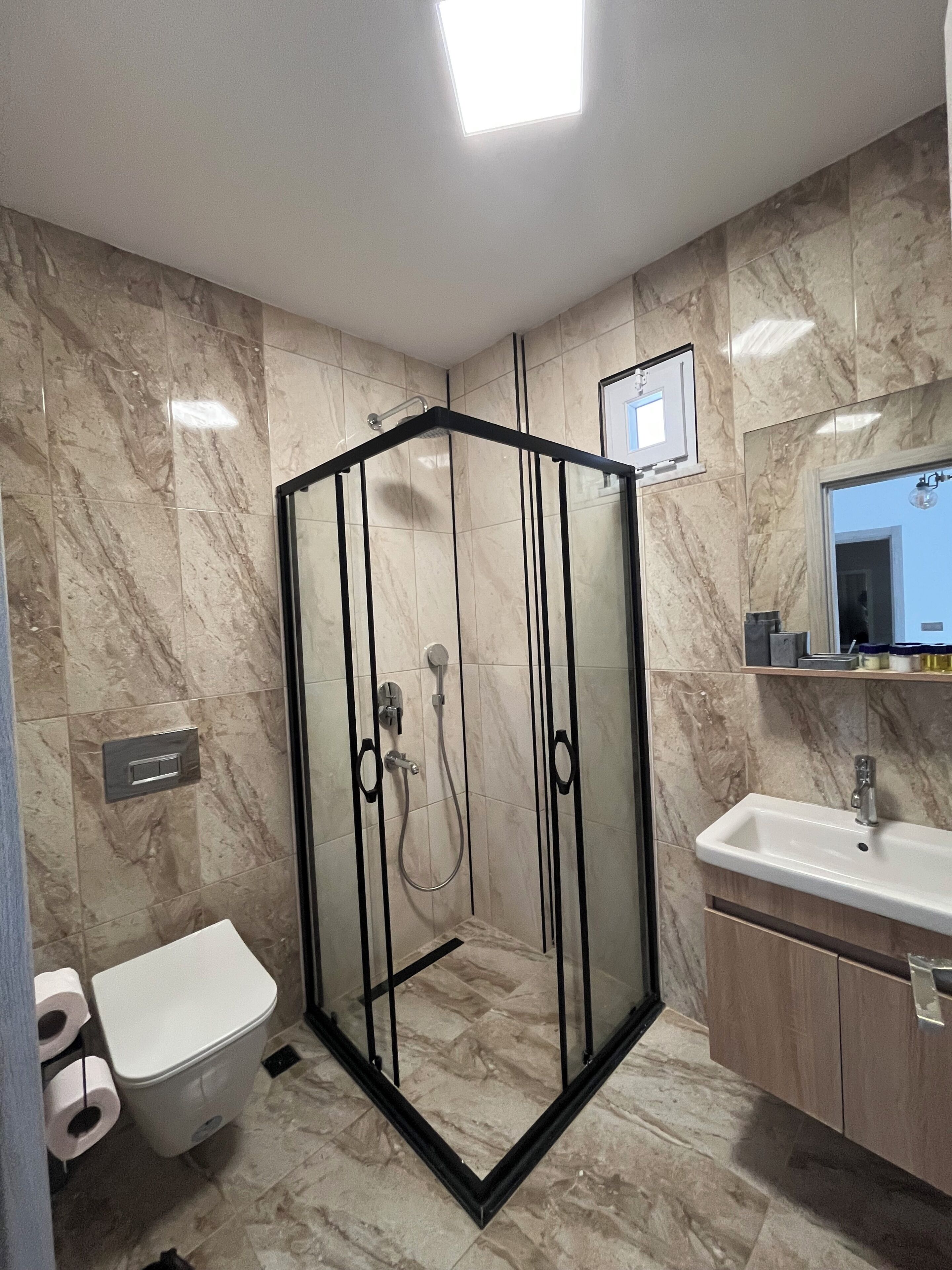 A modern bathroom with a glass-enclosed shower, a toilet, and a sink.