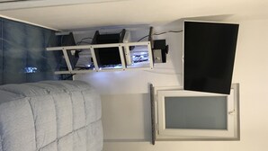 A bedroom with a bed, a mounted TV, and a shelf with electronic devices. - APARTMENT IN VILLA (SANGINETO)