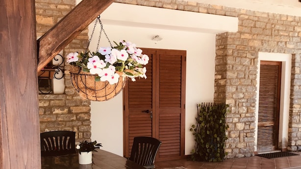 A patio with a table and chairs, a hanging flower basket, and stone walls. - APARTMENT IN VILLA (SANGINETO)