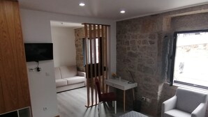 A modern hotel room with a sofa, a desk, a chair, and a TV.