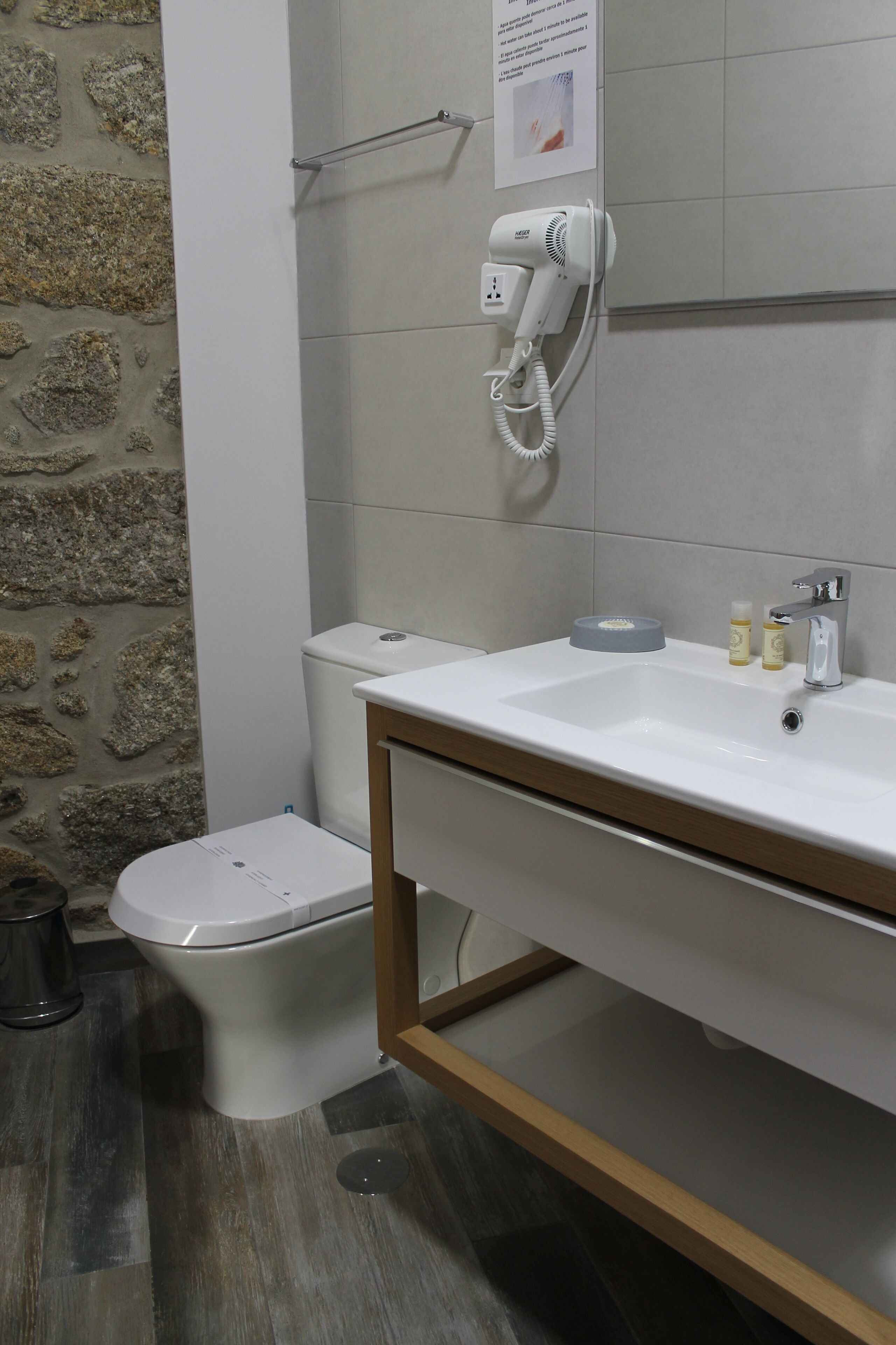 A bathroom with a white sink, a toilet, and a hairdryer mounted on the wall.