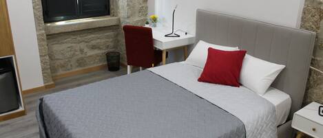 A bedroom with a bed, a desk, and a chair.
