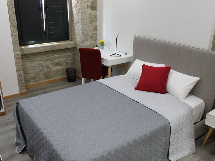 A bedroom with a bed, a desk, and a chair.