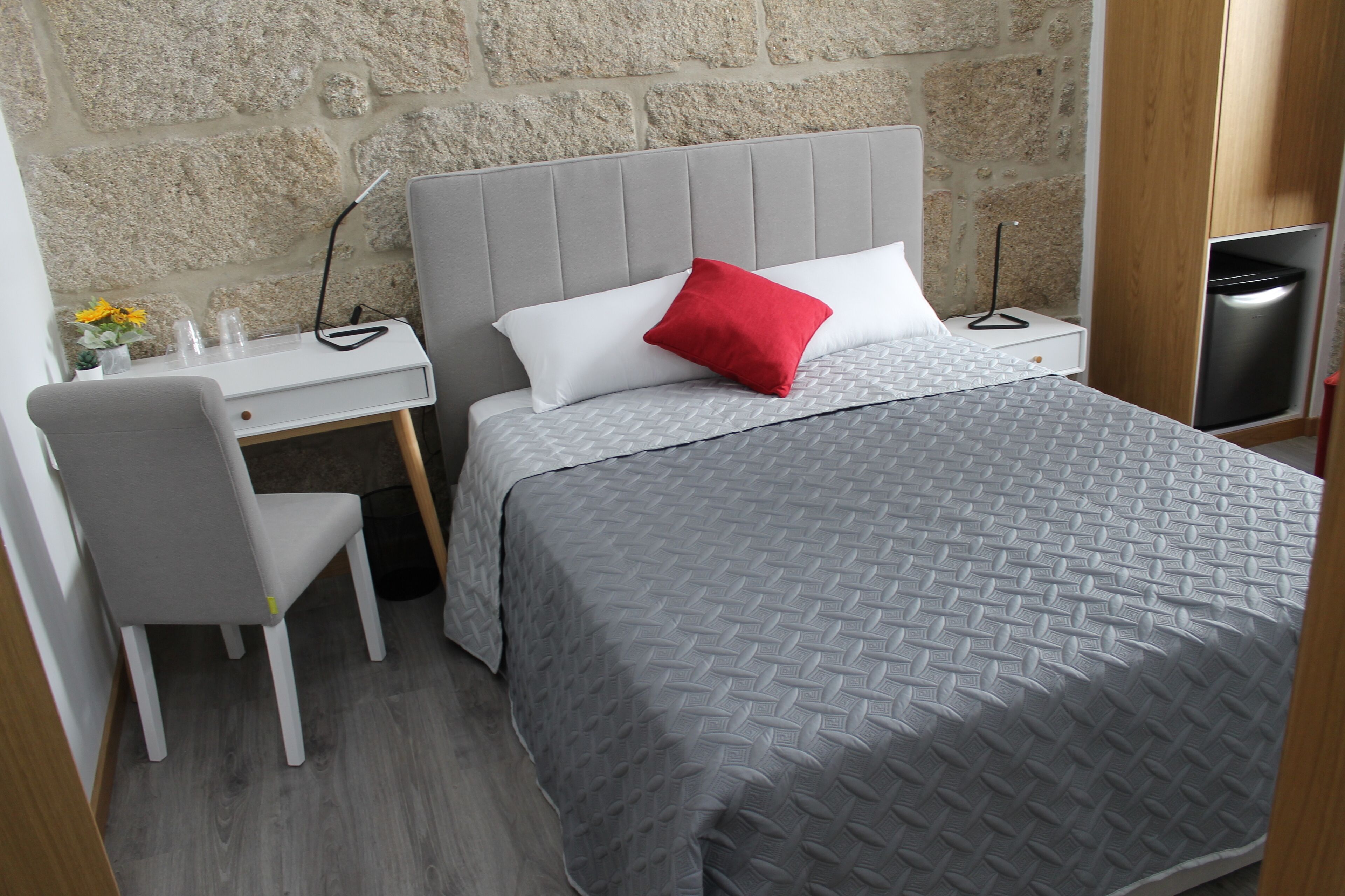 Un dormitorio con una cama, un escritorio, una silla y una mesita de noche.