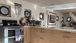 Une cuisine moderne dotée d’un îlot central, d’un four encastré, d’un four à micro-ondes et de divers ustensiles de cuisine.