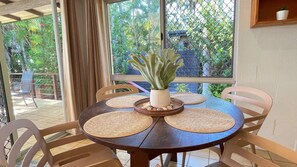 A round wooden table with four woven placemats and a potted plant in the center.