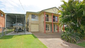 A two-story house with a garage, a covered boat storage area, and a well-maintained lawn.