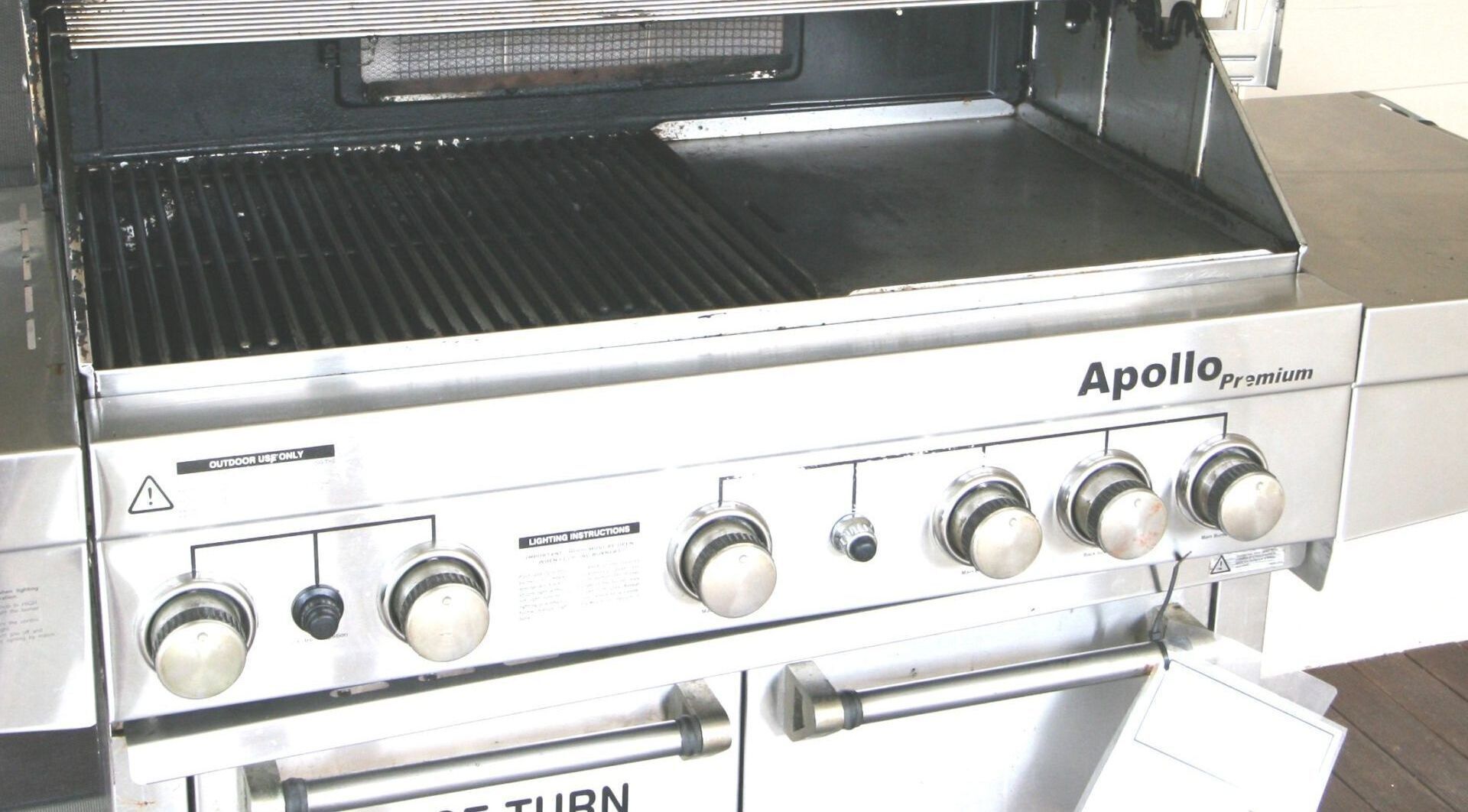 En grill i rustfrit stål, Apollo Premium, med fire knapper, et kontrolpanel og et ventileret tilberedningsområde.
