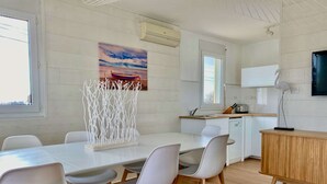A modern kitchen with white cabinets, a wooden countertop, and a dining area with a white table and chairs.