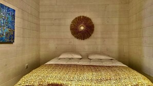 A room with a bed, a circular wall decoration, and a blue painting on the wall.