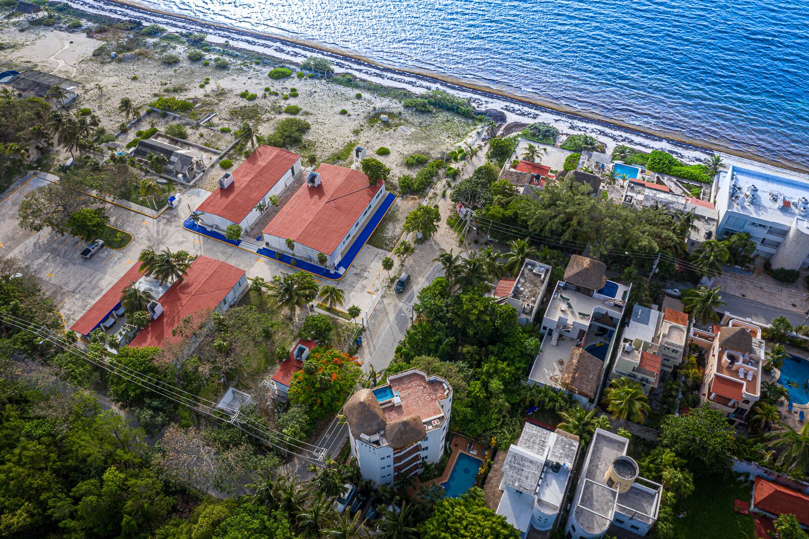 Vue aérienne d’une zone côtière avec des bâtiments, une plage et une piscine.