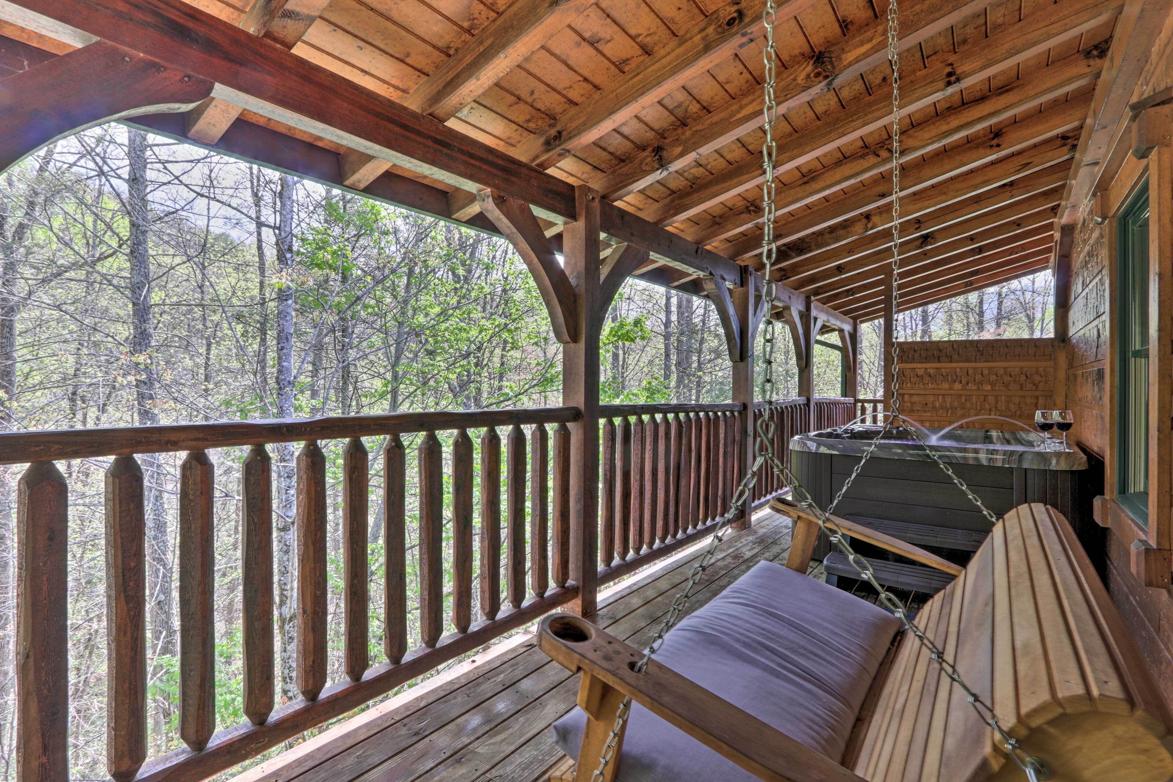 A wooden deck with a swing chair and a hot tub.