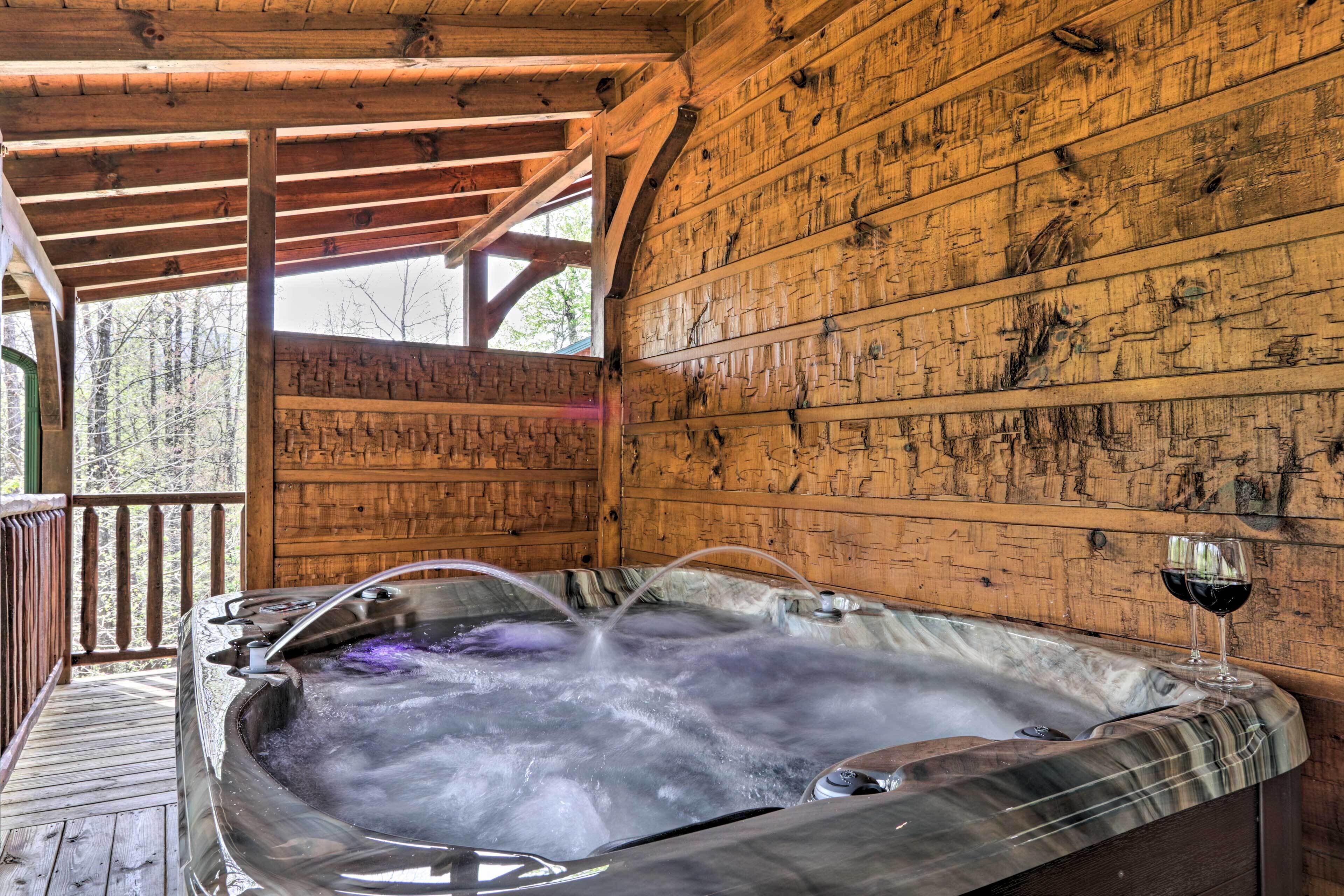 A wooden cabin with a hot tub and two glasses of red wine.
