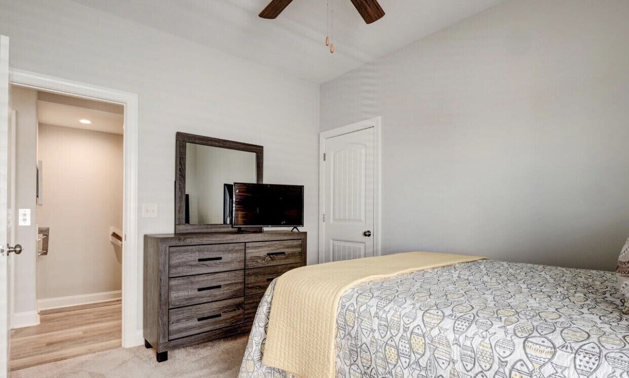 A bedroom with a bed, a dresser, a mirror, and a door.