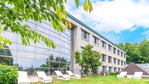 A modern building with large glass windows, a well-maintained lawn, and outdoor seating areas. - Love Dog Resort Izukogen (Ito)