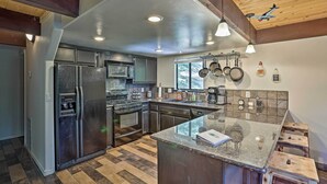 Una cocina moderna con armarios oscuros, electrodomésticos de acero inoxidable y una isla grande con taburetes.