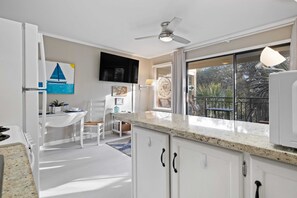 A modern kitchen with white cabinets, a granite countertop, and a dining area with a white table and chairs.