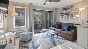 Un salon comprenant un canapé, une table basse, un pouf et un ventilateur de plafond.