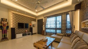 A modern living room with a flat-screen TV, a wooden coffee table, a sofa, and a decorative mask on the wall. - Sugar Baby B&B (Wujie)