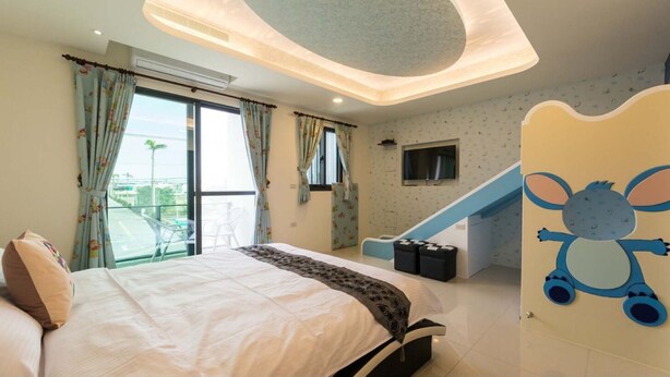 A bedroom with a bed, a window with curtains, a staircase, and a wall with a cartoon character. - Sugar Baby B&B (Wujie)