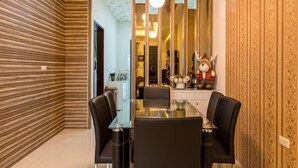 A modern dining area with a glass table, black chairs, and a decorative reindeer figure on the wall. - Sugar Baby B&B (Wujie)
