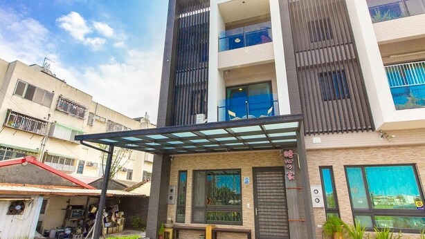 A multi-story building with a covered entrance area, large windows, and a visible balcony on the upper floors. - Candy House (Wujie)