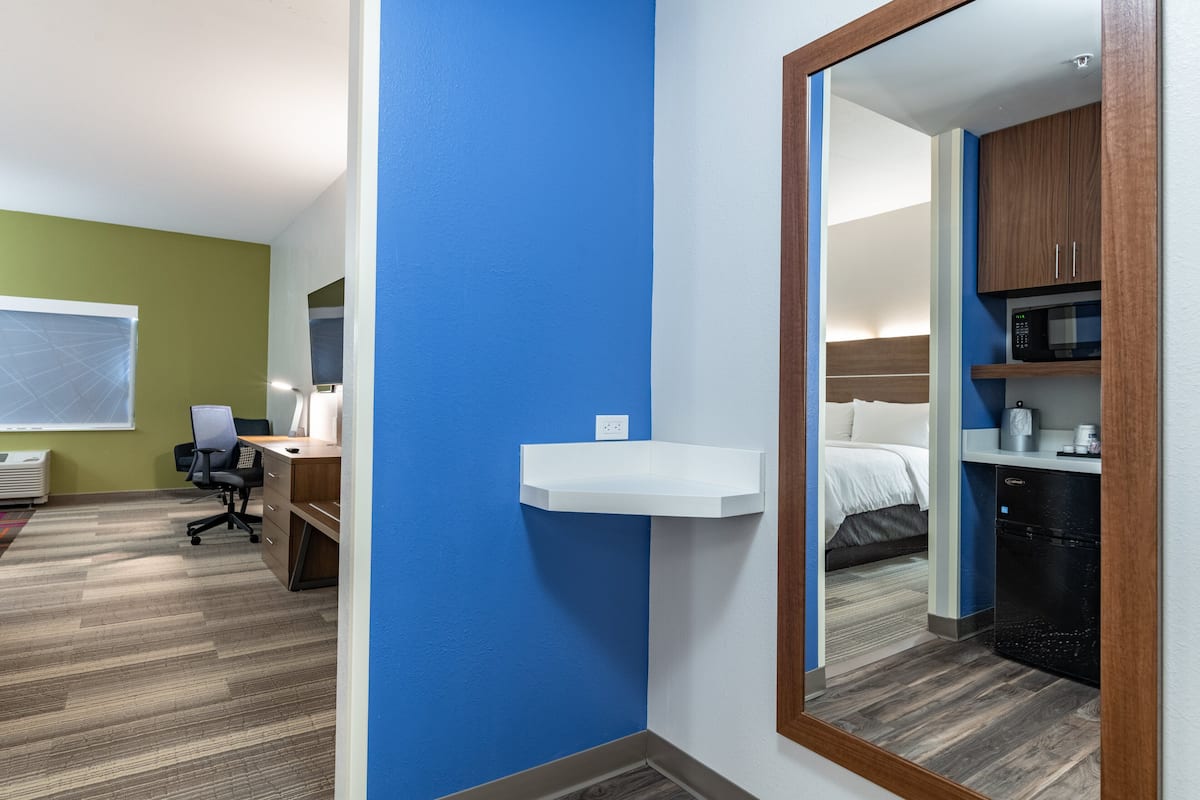 A hotel room with a desk, chair, and a bed.