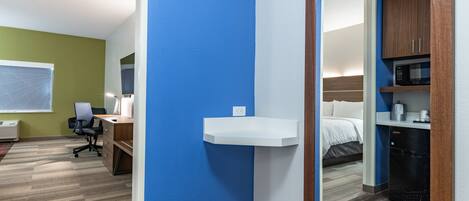 A hotel room with a desk, chair, and a bed.