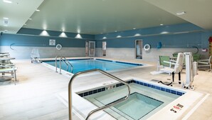 An indoor swimming pool with a no diving sign, a lifeguard chair, and a pool ladder.