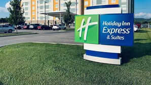 A Holiday Inn Express & Suites building with a clear sky and a parking lot in front.