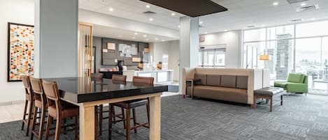 A modern interior with a dining area, a sofa, and a view through large windows.