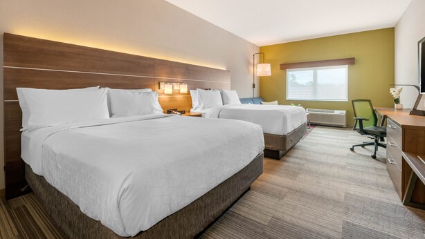 A hotel room with two beds, a desk, and a chair.