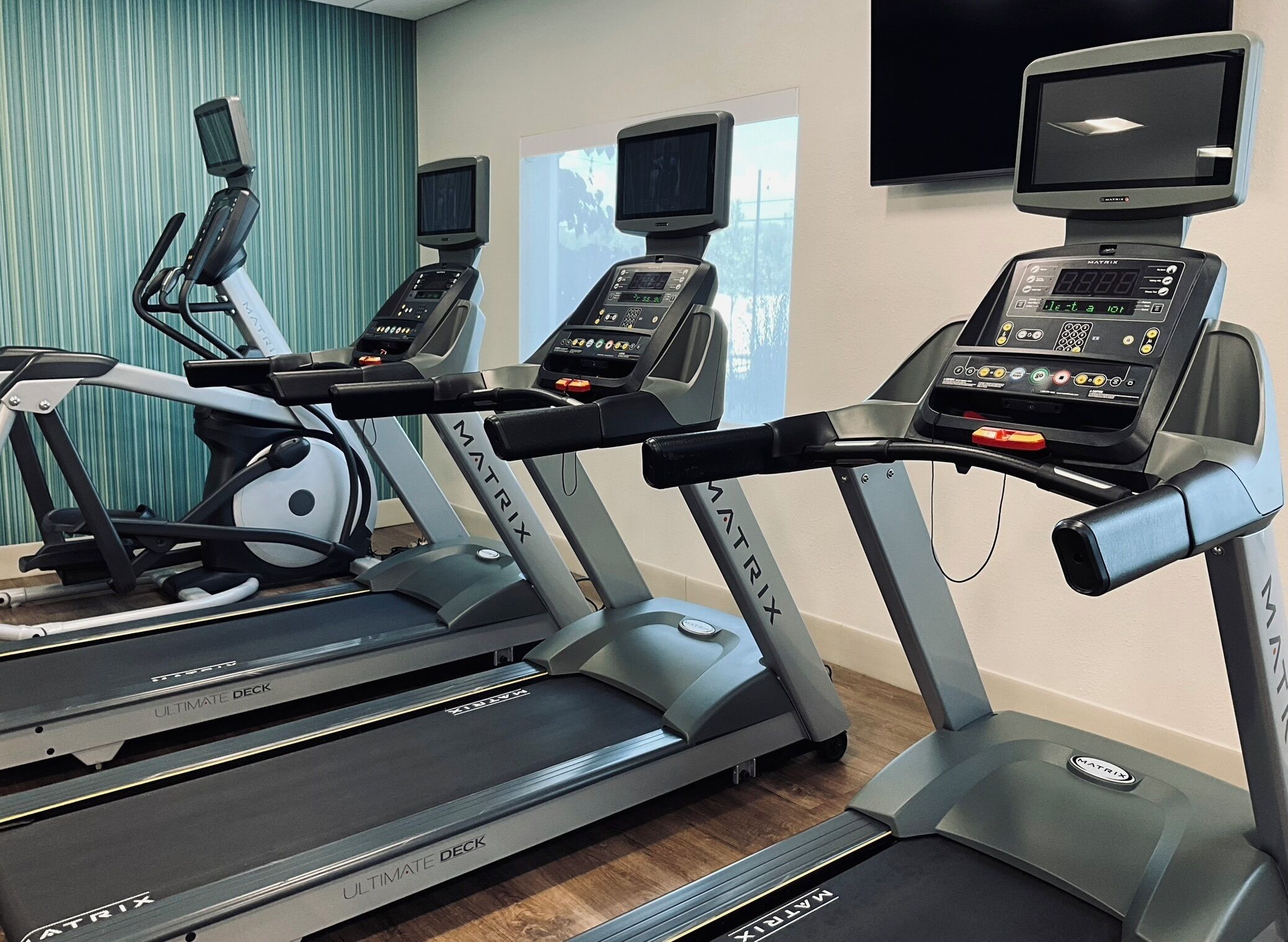 Un gimnasio con cintas de correr MATRIX, una bicicleta estática y una máquina de remo.