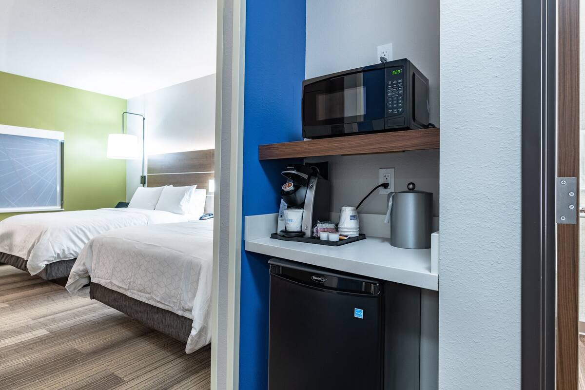 Habitación de hotel con cama, microondas, cafetera y lavavajillas.