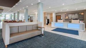 A spacious lobby with a reception desk, seating area, and a large window providing natural light.