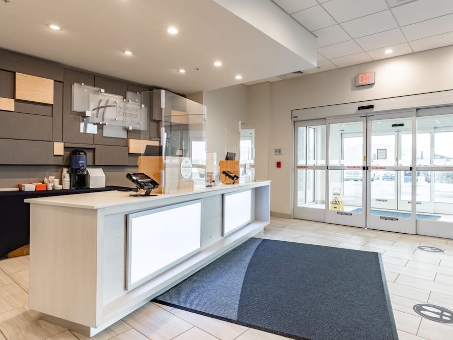 A hotel reception area with a counter, a coffee machine, and a glass door leading outside.