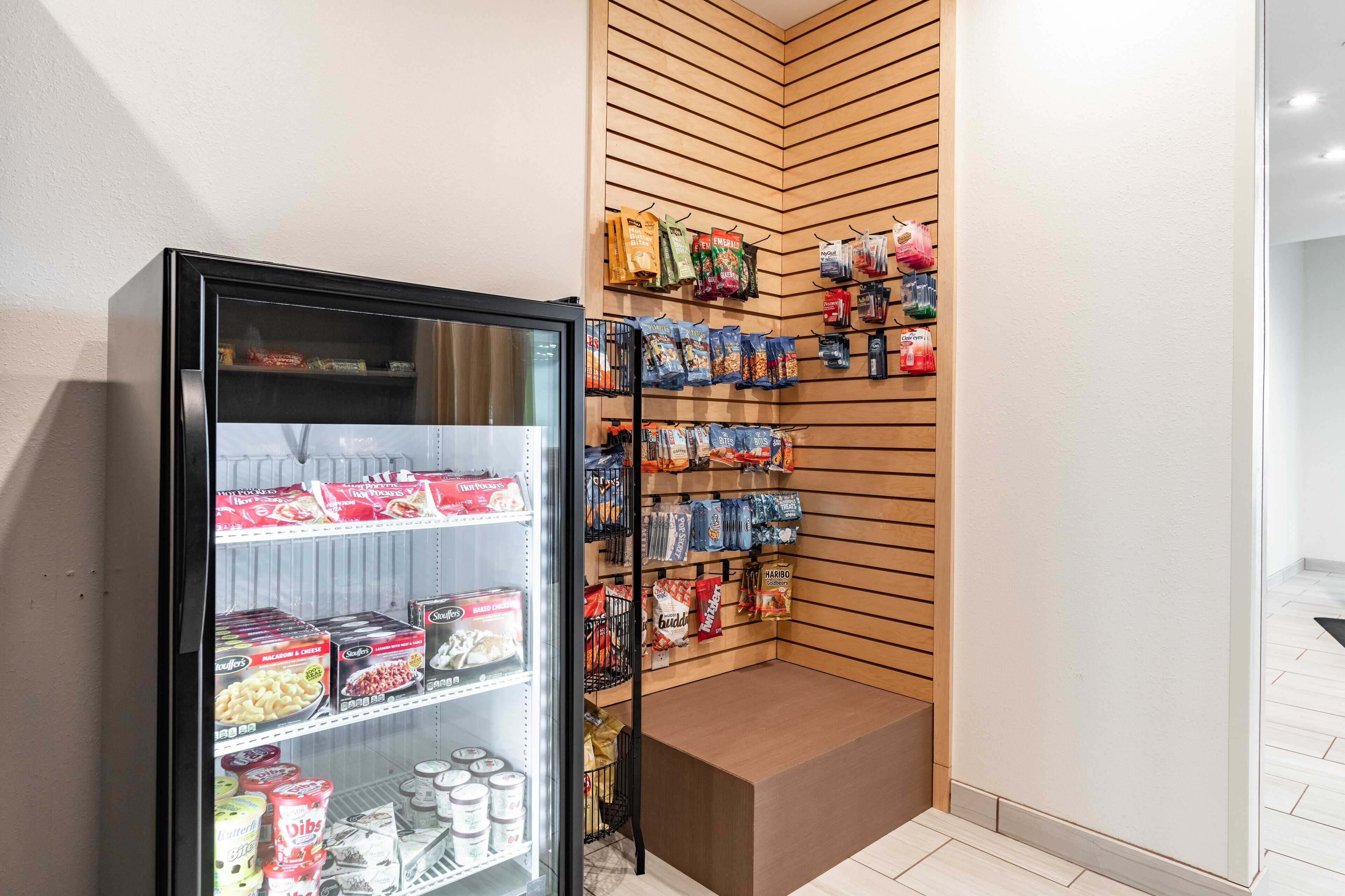 A refrigerated display with various packaged goods and a snack wall.