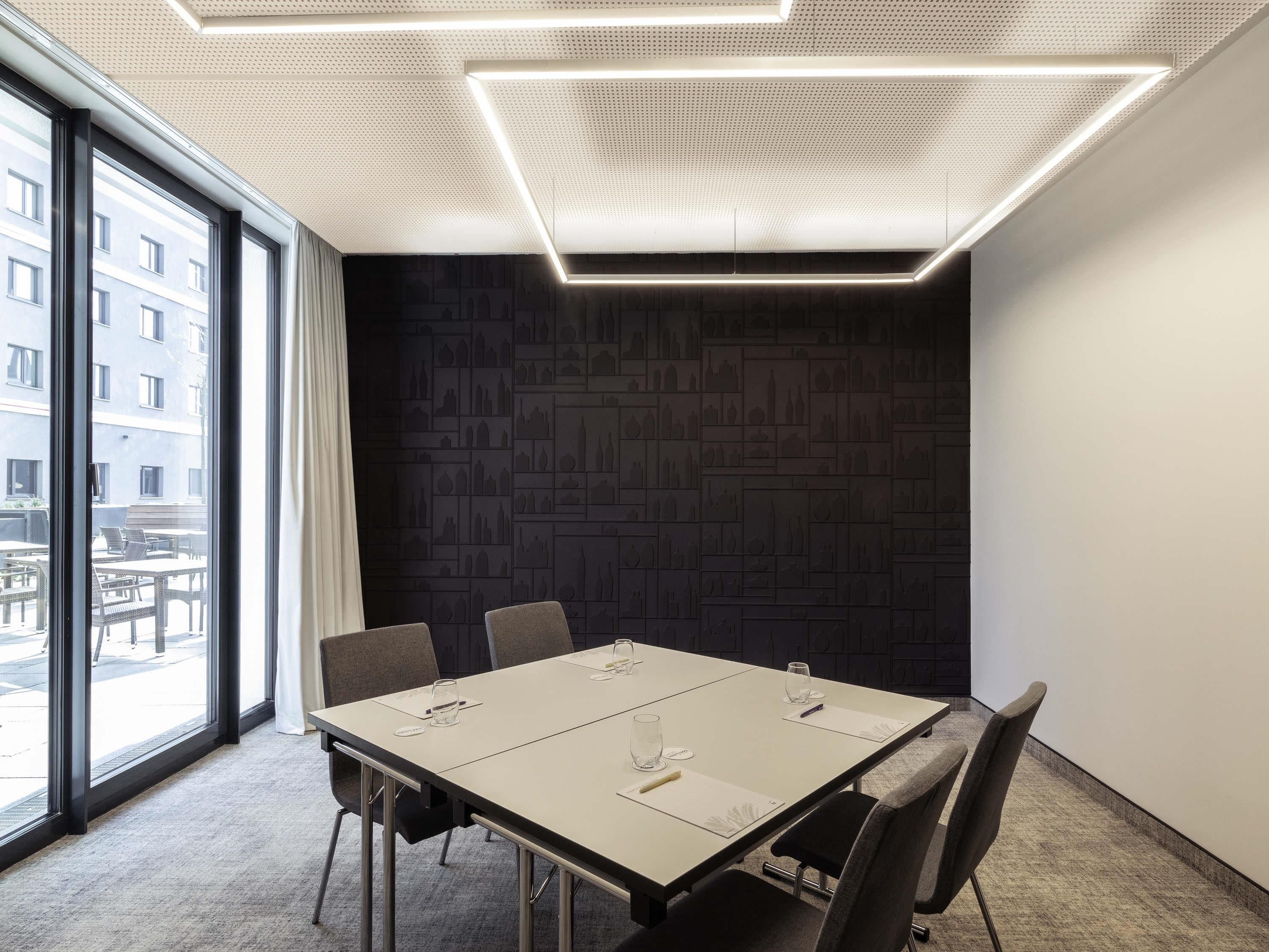 A conference room with a large table, chairs, and a cityscape view through large windows.