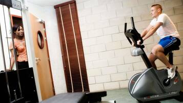 A gym with a stationary bike, a bench, and a mirror.
