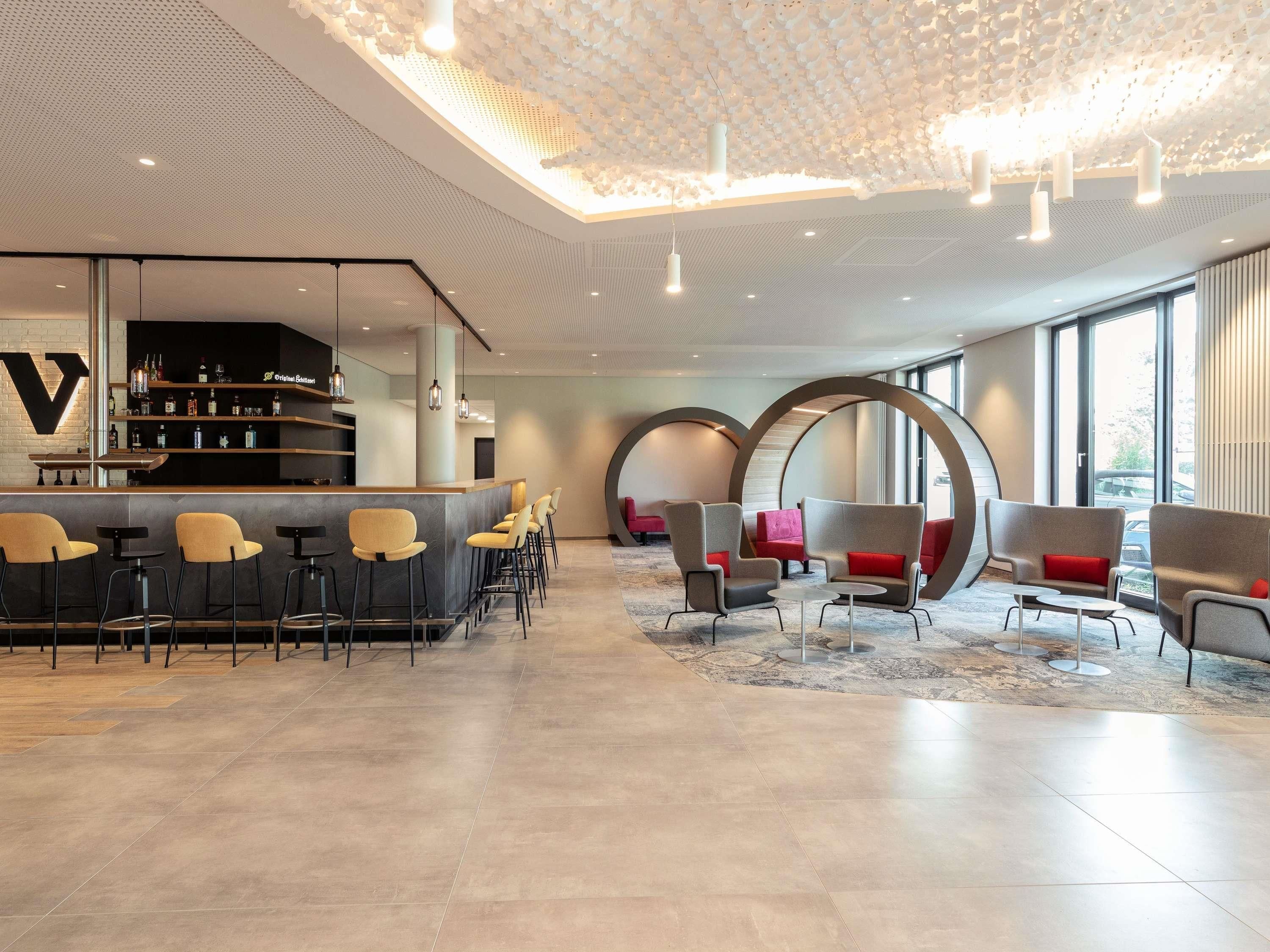 Uma área de bar moderna com balcão, assentos e um design de teto singular.