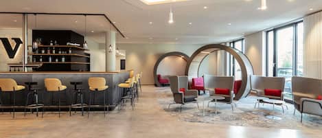Un área de bar moderna con mostrador, asientos y un diseño de techo singular.