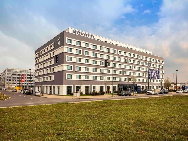 Een Novotel hotel met een modern design, meerdere verdiepingen en een parkeerplaats ervoor.