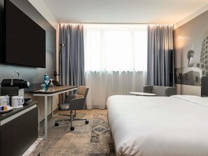 Une chambre d’hôtel comprenant un lit, un bureau avec un téléphone, une chaise et une petite table.