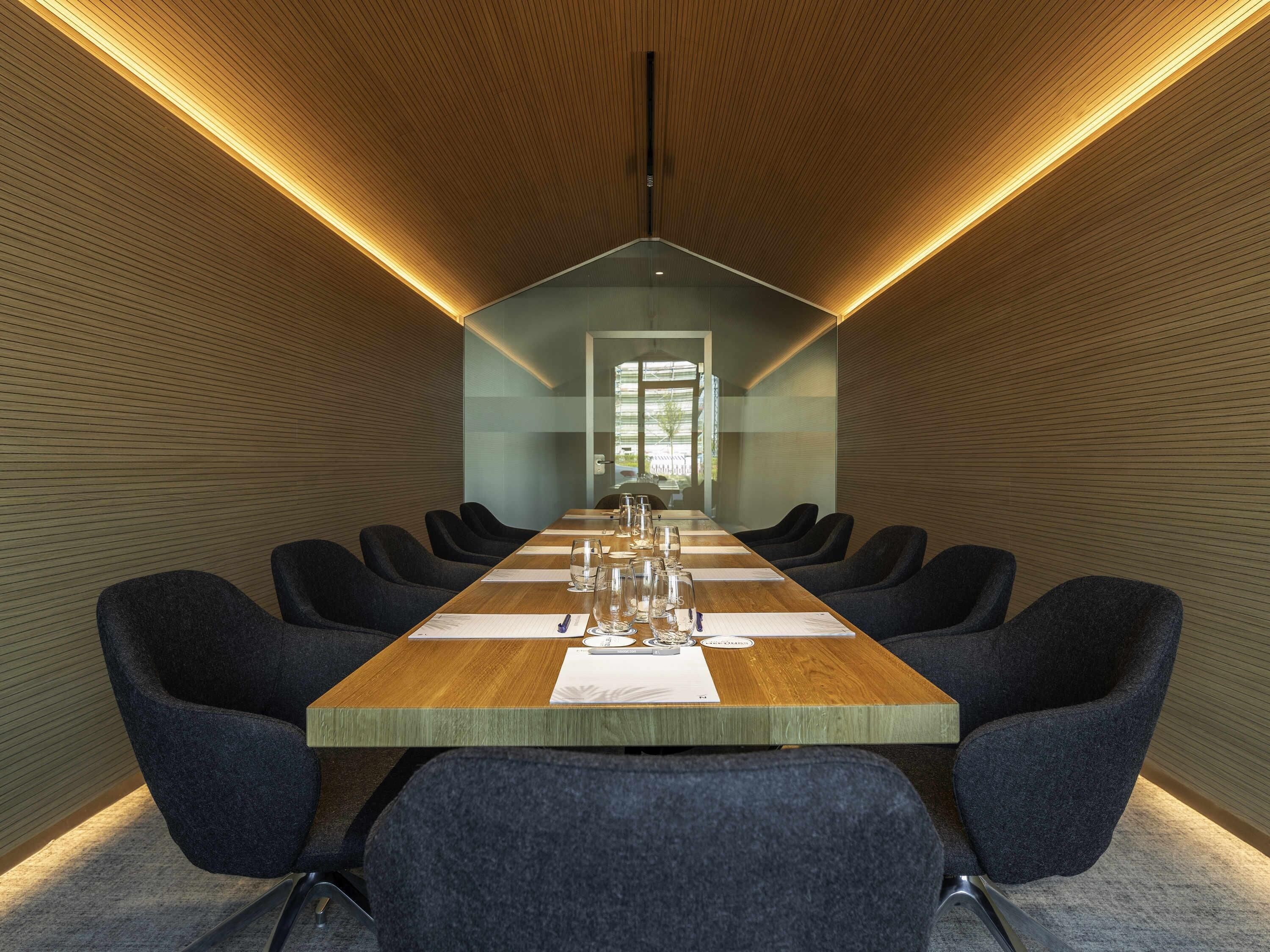 A conference room with a long table, chairs, and a modern design.