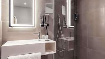 Et moderne badeværelse med en glasafskærmet brusekabine, et toiletbord med spejl og en håndklædestang.