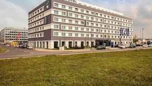 Un hôtel Novotel au design moderne, avec plusieurs étages et un parking situé à l’avant.