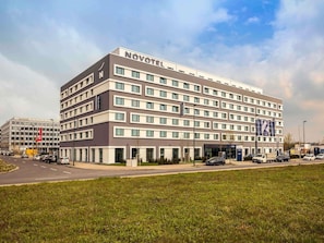 Een Novotel hotel met een modern design, meerdere verdiepingen en een parkeerplaats ervoor.